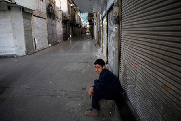 (210410) -- TEHRAN, April 10, 2021 -- A boy sits by closed shops at the Grand Bazaar in Tehran, Iran, April 10, 2021. Iran on Saturday enforced a 10-day restriction throughout the country to curb the recent resurgence of coronavirus cases and deaths. (Photo by Xinhua) IRAN-TEHRAN-COVID-19-NATIONWIDE RESTRICTIONS-IMPOSED AhmadxHalabisaz 