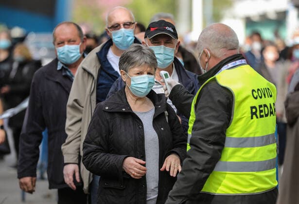 PXL_Mass vaccination in Zagreb Covid ranger measures a woman s temperature in front Zagreb Fair hall during a mass vaccination at Zagreb Fair hall in Zagreb,Croatia on April 12, 2021.By the end of the day 5,000 citizens should receive the AstraZeneca COVID-19 vaccine JuricaxGaloic PIXSELL
