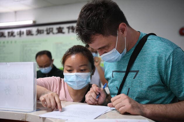 Coronavirus in China, Impfstart für Ausländer in Peking (210415) -- GUANGZHOU, April 15, 2021 -- A Russian national (1st, R) registers for COVID-19 vaccination at a hospital in Yuexiu District of Guangzhou, south China s Guangdong Province, April 15, 2021. Guangdong Province started administering COVID-19 vaccines to foreigners in the province on April 15 on a voluntary basis. Foreign nationals who are covered by the local health insurance program can be vaccinated for free, enjoying the same policy as insured Chinese citizens, and those not covered will be charged 100 yuan (about 15 U.S. dollars) per dose. ) CHINA-GUANGDONG-FOREIGNERS-COVID-19-VACCINATION (CN) DengxHua 