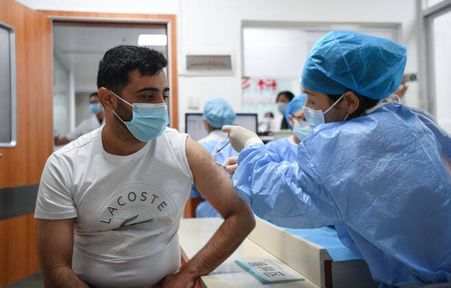 Coronavirus in China, Impfstart für Ausländer in Peking (210415) -- GUANGZHOU, April 15, 2021 -- A Chilean national (L) receives a dose of COVID-19 vaccine at a hospital in Yuexiu District of Guangzhou, south China s Guangdong Province, April 15, 2021. Guangdong Province started administering COVID-19 vaccines to foreigners in the province on April 15 on a voluntary basis. Foreign nationals who are covered by the local health insurance program can be vaccinated for free, enjoying the same policy as insured Chinese citizens, and those not covered will be charged 100 yuan (about 15 U.S. dollars) per dose. ) CHINA-GUANGDONG-FOREIGNERS-COVID-19-VACCINATION (CN) DengxHua 