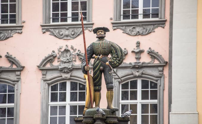 Schaffhausen, Schweiz - 17. April 2021: Der Soldat auf dem Landknechtbrunnen auf dem Schaffhauser Fronwagplatz schaut kritisch zu den Corona-Massnahmen-Kritiker.