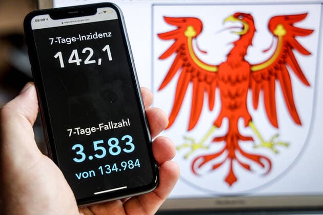 Coronavirus in Germany Covid 19 Dashboard of the Robert Koch Institute DEU, Germany, Brandenburg, 18 04 2021 The 7-day incidence for the state Cases last 7 days 100 000 PE is displayed on an iPhone, with the state coat of arms in the background.