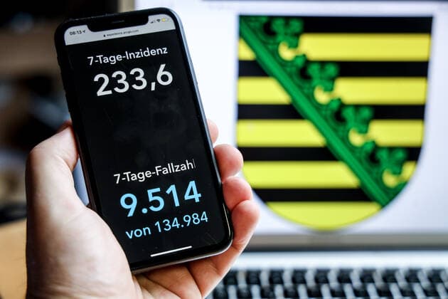 Coronavirus in Germany Covid 19 Dashboard of the Robert Koch Institute DEU, Germany, Saxony, 18 04 2021 The 7-day incidence for the state Cases last 7 days 100 000 p.e. is displayed on an iPhone, with the state coat of arms in the background