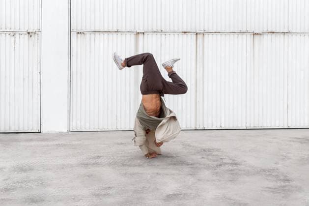 Unrecognizable male dancer showing breakdance movement while balancing on arms and performing Hand Hops on concrete ground in urban area Copyright: xPicuaxEstudiox Model Released