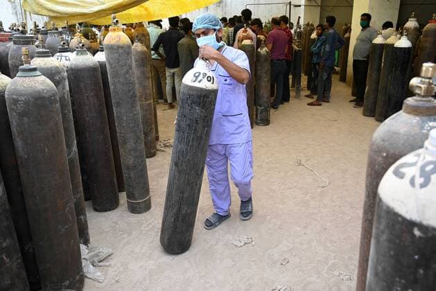 COVID-19 outbreak in India A health worker carries a cylinder filled with medicated oxygen after refilling at a plant as corona virus cases surge across Prayagraj. Allahabad Uttar Pradesh India Copyright: PrabhatxKumarxVerma