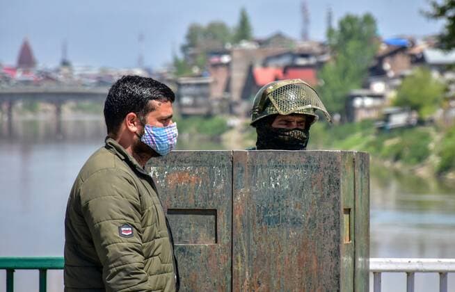 April 25, 2021, Kashmir, Jammu & Kashmir, India: A man wearing a facemask as a precaution against the spread of covid-19 walks past a paramilitary trooper during the imposed curfew..Amid the second wave of the pandemic sweeping across the India, Authorities in Kashmir imposed a 34-hour curfew on Saturday. The curfew which was imposed at 8 pm on Saturday will remain effective till 6 am on Monday. Meanwhile, India s coronavirus cases and deaths hit a new record with 3.49 lakh fresh infections, taking the case load to 1.69 crore, 2,767 people died in the last 24 hours. Kashmir India - ZUMAs197 20210425_zaa_s197_020 Copyright: xSaqibxMajeedx