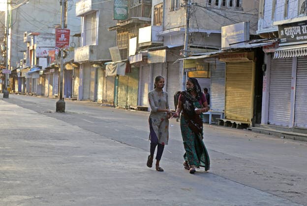 India: Weekend curfew due to COVID pandemic in Rajasthan Women walk through in front of closed shops at a market during weekend curfew amid surge in coronavirus cases across the country, in Beawar. Beawar Rajasthan India Copyright: SumitxSaraswat