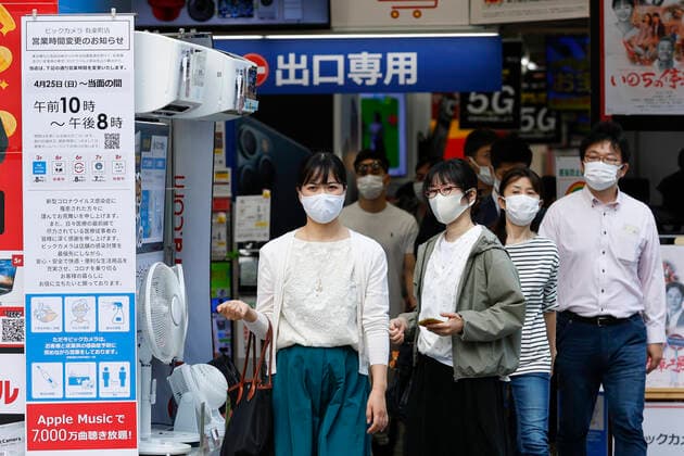 April 25, 2021, Tokyo, Japan: People wearing face masks walk past a signboard announcing the business hours under the new state of emergency in Tokyo. The third state of emergency started today, April 25 through May 11, in Tokyo, Osaka, Kyoto, and Hyogo to curb infections of coronavirus cases. Tokyo Japan - ZUMAm191 20210425_zap_m191_033 Copyright: xRodrigoxReyesxMarinx