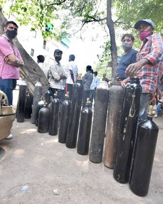 NEW DELHI, INDIA - APRIL 26: Family members of patients stand with empty oxygen cylinders outside the oxygen filling center at Bhogal on April 26, 2021 in New Delhi, India. (Photo By Sonu Mehta Hindustan Times) India Faces Oxygen Crisis As Covid-19 Cases Mount