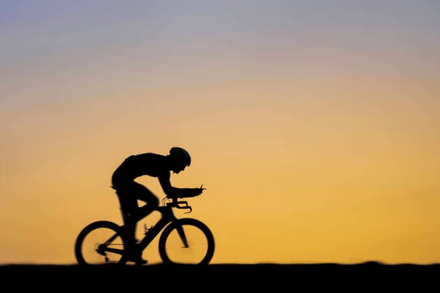 Male triathlete riding bicycle during sunset model released Symbolfoto STSF02893