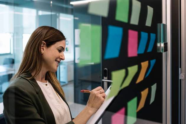 IMAGO Creative: Kreative Renaissance -- der junge Entrepreneur Female entrepreneur planning strategies while standing near glass wall with adhesive note at office model released Symbolfoto property released XLGF01417