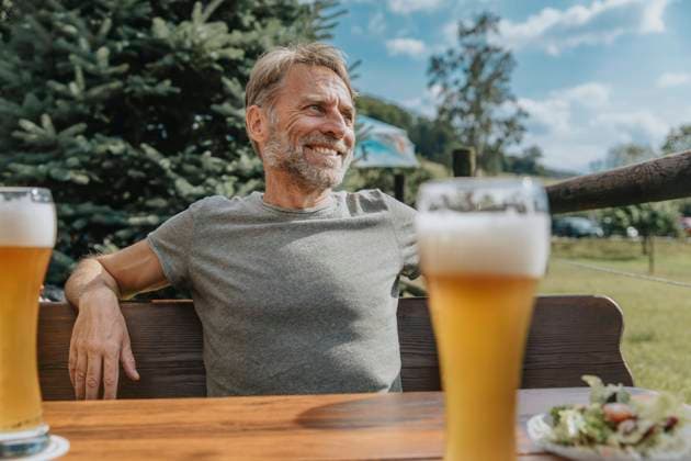 Creative Highlights Symbolbilder Smiling mature man looking away while sitting in beer garden model released Symbolfoto MFF07644
