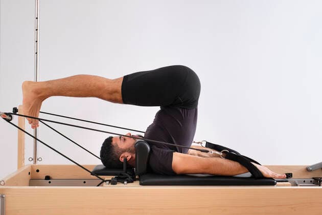 Mid adult man practicing pilates on machine in health club model released Symbolfoto property released AODF00352
