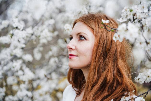 IMAGO Creative: Jahreszeit Frühling, Frühlingsanfang am 20. März Redhead woman amidst white almond tree looking away model released Symbolfoto EBBF02947
