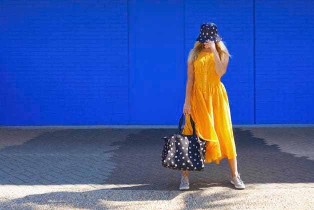 Mature woman with duffel bag and bucket hat in front of blue wall model released Symbolfoto AZF00274