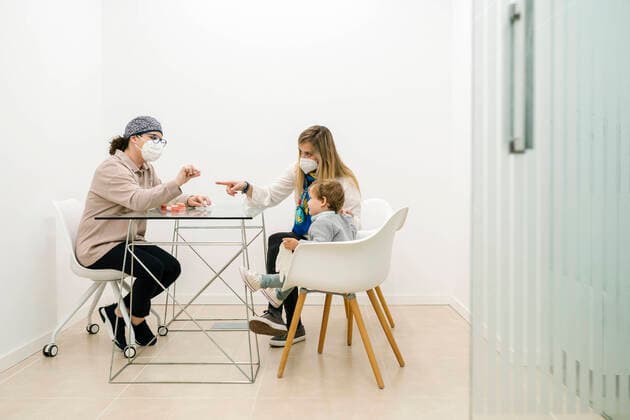 Pediatric dentist talking to boy sitting with mother at office model released Symbolfoto property released EGAF02165