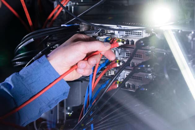 Male IT engineer connecting patch cord cable in server rack model released Symbolfoto property released FKF04131