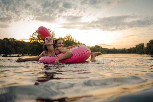 Friends having fun on a lake on a pink flamingo floating tire model released Symbolfoto GUSF02325