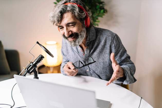 Senior male professional discussing while podcasting over laptop at office model released Symbolfoto property released JCZF00598