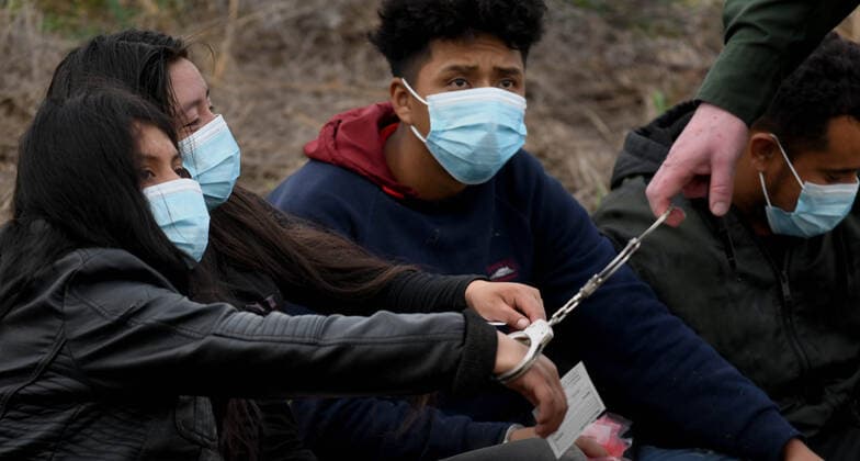 April 27, 2021, La Joya, Texas, USA: A border Agent grabs one end of handcuffs to move a girl as asylum-seeking migrants are processed after crossing border from Mexico in La Joya. A surge has been overwhelming U.S. facilities at the southern borders. La Joya USA - ZUMAg208 20210427_zap_g208_011 Copyright: xCarolxGuzyx