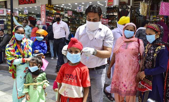 AMRITSAR, INDIA - APRIL 27: Members of National Human Rights & Crime Control Organization helping a child with a face mask during an awareness campaign against the spread of Covid-19 at Heritage street on April 27, 2021 in Amritsar, India. (Photo by Sameer Sehgal Hindustan Times) NGO Distributes Facemasks During An Awareness Campaign Against The Spread Of Covid-19 In Amritsar