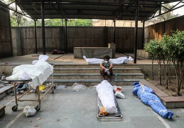 April 28, 2021, New Delhi, India: (EDITORS NOTE: Image depicts death).A man wearing a face mask sits next to the bodies of those who have died from the coronavirus Covid-19 virus for cremation at a crematorium..India faces the world fastest growing number of Covid-19 cases with 360,927 new confirmed infections, the highest single day count in the country and more than 3,293 death in the month of April 2021. New Delhi India - ZUMAs197 20210428_zaa_s197_066 Copyright: xNaveenxSharmax