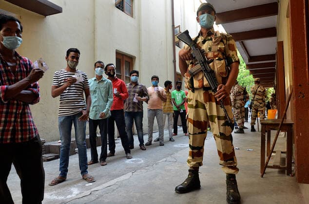 India: Eight phase of West Bengal state elections A paramilitary soldier stands guard as voters wait outside at a polling station during the eight phase of West Bengal state elections in Kolkata in India. India Copyright: SanjayxPurkait