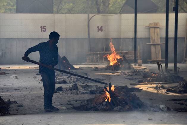 NEW DELHI, INDIA - APRIL 29: A man stoking a funeral pyre at the Subhash Nagar Crematorium, on April 29, 2021 in New Delhi, India. (Photo by Sanjeev Verma Hindustan Times) Cremation Of Covid-19 Victims