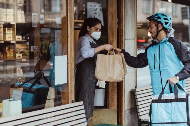 Young delivery man collecting order from female owner at delicatessen shop during COVID-19 Sweden, Stockholm, model released, property released Copyright: xMaskotx , MA85991