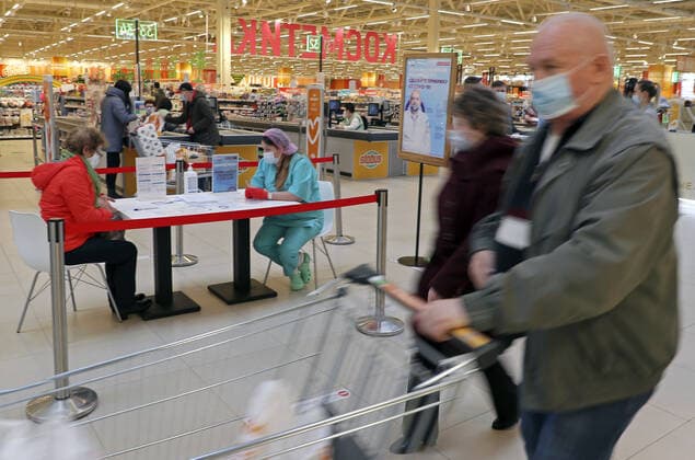 MOSCOW, RUSSIA â€” APRIL 30, 2021: Shoppers push a trolley as a woman (L back) fills in paperwork before receiving the Gam-COVID-Vac vaccine (under the brand name of Sputnik V) at a temporary vaccination site in the Globus superstore. A mobile vaccination team is providing vaccines free of charge and without prior sign-up. Since the start of the pandemic, Moscow has confirmed more than 1,092,800 cases of COVID-19. Since the beginning of April, the number of new confirmed cases has been increasing in the Russian capital by more than 1,500 daily. Gavriil Grigorov TASS  TS0FEB32