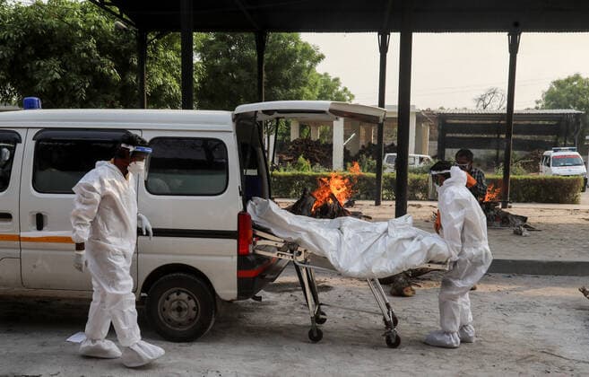 News Bilder des Tages April 30, 2021, New Delhi, India: (EDITORS NOTE: Image depicts death).Health workers wearing Personal Protective Equipment (PPE) transport the body of Covid-19 victim during the mass cremation at Dwarka crematorium..The ongoing vaccination drive will open for 18-45 age group from May 01, 2021. India has recorded 386,452 new coronavirus infection cases and 3,498 death in the last 24 hours. New Delhi India - ZUMAs197 20210430_zaa_s197_074 Copyright: xNaveenxSharmax