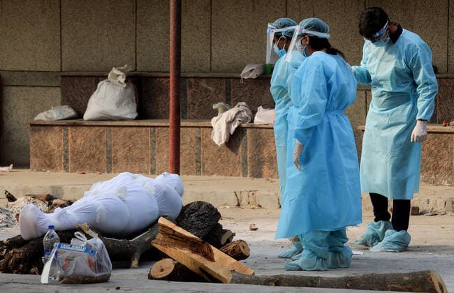 April 30, 2021, New Delhi, India: (EDITORS NOTE: Image depicts death).Grieving family members wearing Personal Protective Equipment (PPE) stand next to the body of their relative who lost his life due to the coronavirus Covid-19 disease during the mass cremation at Dwarka crematorium..The ongoing vaccination drive will open for 18-45 age group from May 01, 2021. India has recorded 386,452 new coronavirus infection cases and 3,498 death in the last 24 hours. New Delhi India - ZUMAs197 20210430_zaa_s197_085 Copyright: xNaveenxSharmax