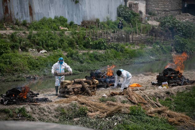 May 3, 2021, Kathmandu, Nepal: Workers wearing personal protective equipment (PPE) prepare funeral pyre for the body of a person who has died of COVID-19 at the premises of Pashupatinath temple in Kathmandu..Electronic crematorium situated in Pashupati is congested with COVID-19 death bodies arriving for cremation. As there is no space inside the crematorium due to limited capacity death bodies of the deceased are being burned near the bank of Bagmati River at the Premises of Pashupatinath temple. Kathmandu Nepal - ZUMAs197 20210503_zaa_s197_010 Copyright: xPrabinxRanabhatx