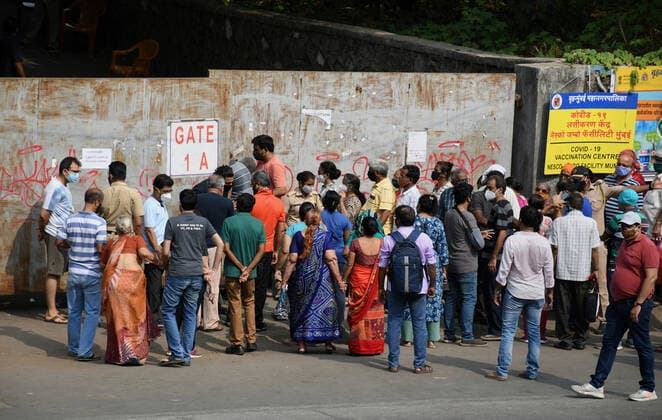 May 5, 2021, Mumbai, India: People wearing face masks stand outside NESCO vaccination center gate to receive their dose of the COVID19 vaccination in Mumbai..Vaccination drive which was stopped for people above 45 years of age last week started again with the availability of vaccine stock. Mumbai India - ZUMAs197 20210505_zaa_s197_031 Copyright: xAshishxVaishnavx