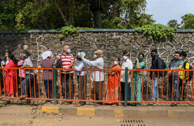 May 5, 2021, Mumbai, India: People wearing face masks stand in a queue outside NESCO vaccination center to receive their dose of the COVID19 vaccination in Mumbai..Vaccination drive which was stopped for people above 45 years of age last week started again with the availability of vaccine stock. Mumbai India - ZUMAs197 20210505_zaa_s197_032 Copyright: xAshishxVaishnavx