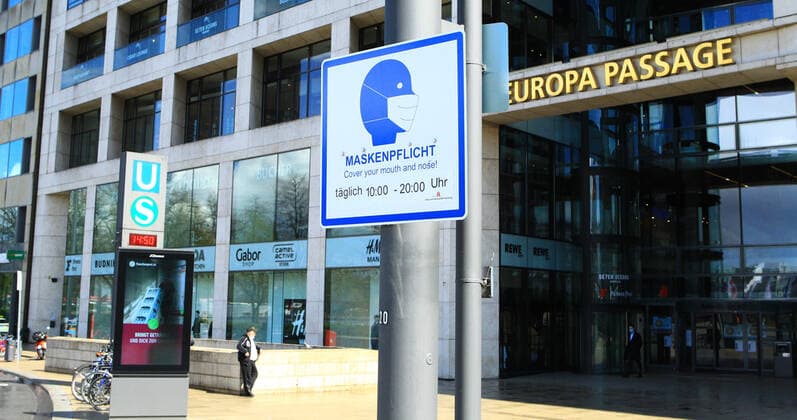 A sign hangs on a pole in front of the Europa Passage in Hamburgs city centre, indicating that masks are compulsory in this area at certain times Altstadt Hamburg