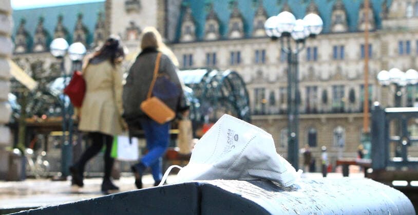 A mouth nose mask lies on a garbage can at the Reesendamm in the Hamburg city center In the background the Hamburg city hall Old Town Hamburg
