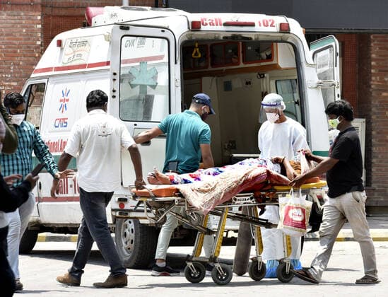 NEW DELHI, INDIA - MAY 9: Medical workers in Personal protective equipment (PPE) with others shifted to a covid corona virus patients on a stretcher outside the Covid-19 ward at Lok Nayak Jai Prakash (LNJP) hospital, on May 9, 2021 in New Delhi, India. (Photo by Sonu Mehta Hindustan Times ) Daily Life Amid Coronavirus Pandemic In India