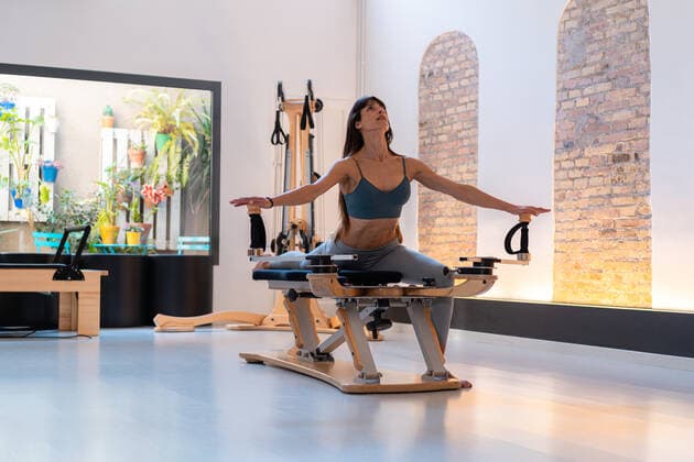 Concentrated fit female stretching legs and doing lunge exercises on pilates reformer during training in gym, Model released Copyright: xEnriquexEspinosax MR