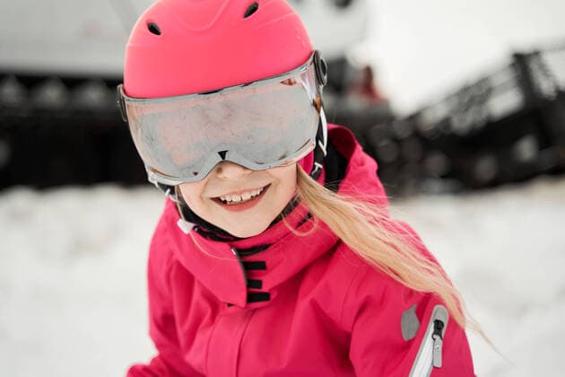 IMAGO Creative: Wintersport, Mode Positive cute girl in pink warm activewear goggles and helmet skiing alongside snowy slope on clear winter day, Model released Copyright: xSergeyxMironovx MR