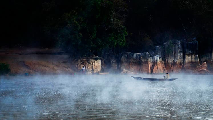 Man in a traditional kayak during a foggy morning on Tsiribihina River, Madagascar Copyright: xCatalinxMarinx