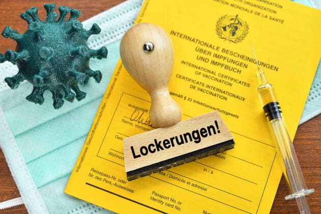 PHOTOMONTAGE, vaccination certificate, coronavirus model, vaccination syringe and stamp with the inscription relaxations ** NUR FUER REDAKTIONELLE ZWECKE ** EDITORIAL USE ONLY **
