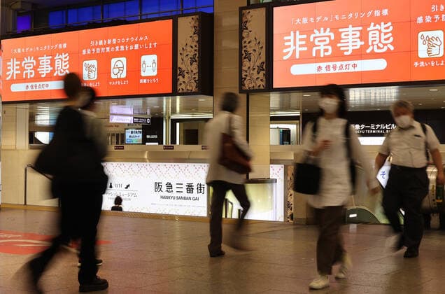 May 15, 2021, Osaka, Japan - People walk under a signage of a COVID-19 state of emergency in Osaka on Saturday, May 15, 2021. Japanese government announced to expand a COVID-19 state of emergency on May 14.  (160323362)