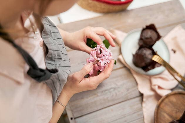 IMAGO Creative: Clickbait, Rezepte und Kochen High angle of crop anonymous female with blossoming flower sprig above table with baked dessert during cooking process at home, Model released Copyright: xSergeyxMironovx MR