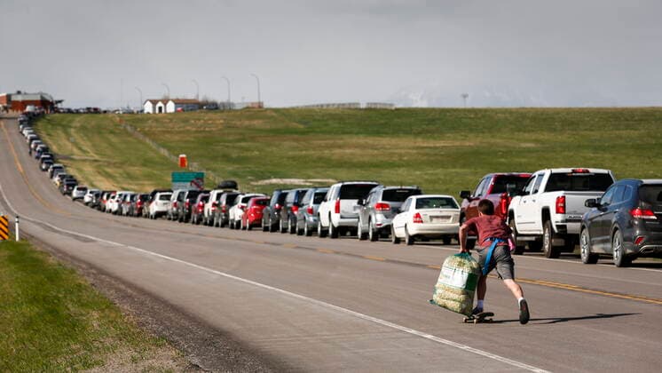 News Bilder des Tages May 18, 2021, Carway, ab, Canada: A teenaged boy uses a skateboard to move up and down selling popcorn to Southern Alberta residents lining up to get shots of a COVID-19 vaccine from a Montana tribe in Carway, Alta., Tuesday, May 18, 2021. Carway Canada  - ZUMAc35_ 20210518_zaf_c35_059 Copyright: xJeffxMcintoshx