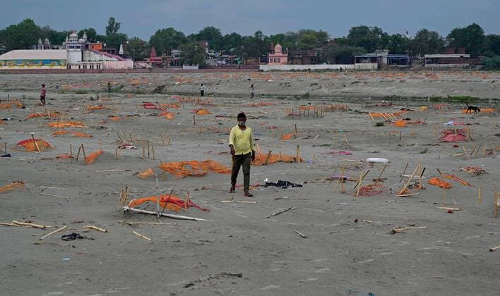 May 19, 2021, Prayagraj, Uttar Pradesh, India: A man walks past shallow graves covered with saffron clothes of suspected Covid-19 coronavirus victims near a cremation ground on the banks of the Ganges River in Shringverpur village, around 40 Km from Allahabad on Wednesday, May 19, 2021. Prayagraj India - ZUMAv115 20210519_zap_v115_017 Copyright: xPrabhatxKumarxVermax