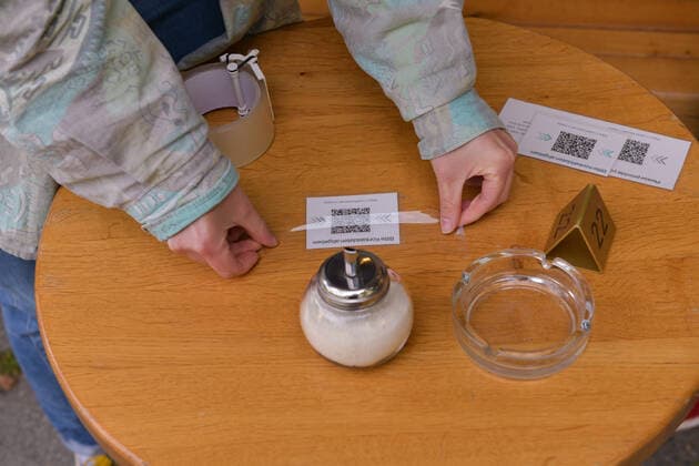 Berlin, Germany 21 May 2021 In Berlin, outdoor restaurants are allowed to reopen after a lockdown to combat the Corona pandemic A person sticks QR codes for the attendance list on the tables of the restaurant Berlin Copyright: xFotostandx xReuhlx