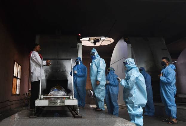 NEW DELHI, INDIA - MAY 21: Relatives of a Covid-19 victim in PPE coveralls perform the last rites at Nigambodh Ghat crematorium, on May 21, 2021 in New Delhi, India. (Photo by Ajay Aggarwal Hindustan Times) Daily Life Amid Coronavirus Pandemic In India
