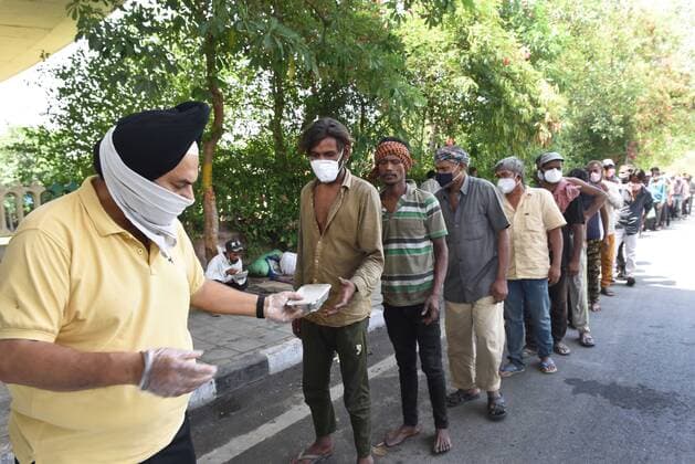 NEW DELHI, INDIA - MAY 21: Daily wage labourers and homeless people line up to collect food during a community feeding session, amid the Covid-19 induced lockdown, near ISBT, on May 21, 2021 in New Delhi, India. (Photo by Ajay Aggarwal Hindustan Times) Daily Life Amid Coronavirus Pandemic In India