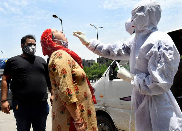 NEW DELHI, INDIA - MAY 21: A health worker takes a swab sample of a woman, during a road-side test for Covid-19, at Kewal Park, on May 21, 2021 in New Delhi, India. ( Photo by Sonu Mehta Hindustan Times) Medical Team Conducts COVID-19 Coronavirus Test